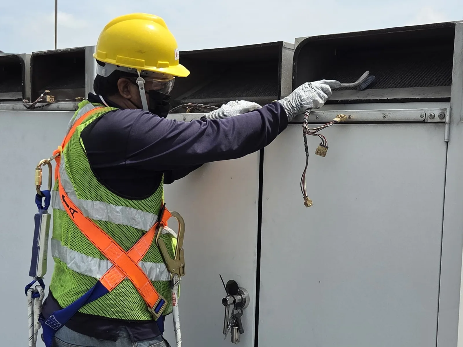 CCST technician brush-cleaning the air intakes of a climate-control unit cabinet